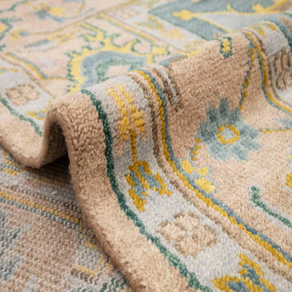 Turkish Oushak hand-knotted rug with faded tribal motif in pastel peach, aqua, and gold tones.